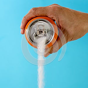 Hand holding a soda can pouring sugar