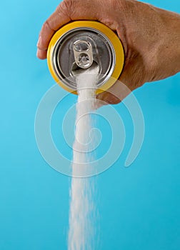 Hand holding a soda can pouring sugar