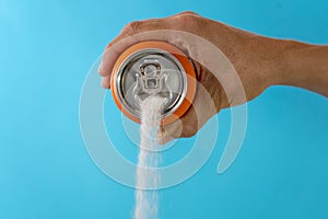 Hand holding a soda can pouring sugar