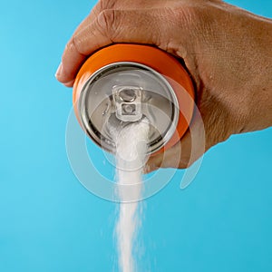 Hand holding a soda can pouring sugar