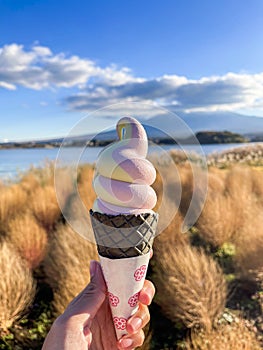 Hand holding soft serve ice cream at Lake Kawaguchiko with Mount Fuji in the background is a popular landmark among