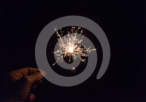 hand holding a sparkler fire on black background