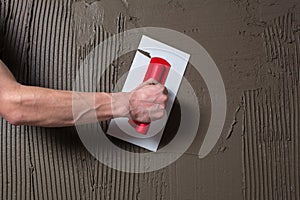 Hand holding a spatula with construction mix and smoothes out bumps.Repair the wall. Plaster the wall with a putty knife.Internal