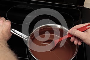 Hand Holding a Spoon and Pan Stirring Cocoa Mixed with Water