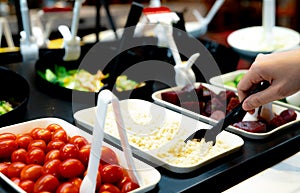 Hand holding spoon to scoop boiled Job`s tears at salad bar. Salad bar buffet at the restaurant. Salad bar buffet for lunch or