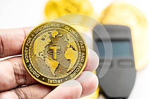 Hand holding a Stable Cryptocurrency USDT coin with hardware wallet in background photo
