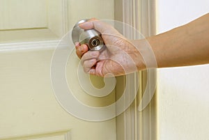 Hand holding steel doorknob closing the door