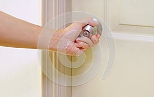 Hand holding steel doorknob to open the door