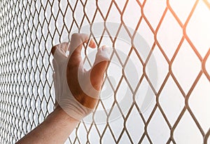 Hand holding steel mesh, The prisoner`s hand captured the steel grate for freedom. The prisoner wants freedom.