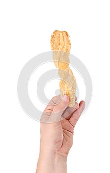 Hand holding stick cracker with sesame seeds.