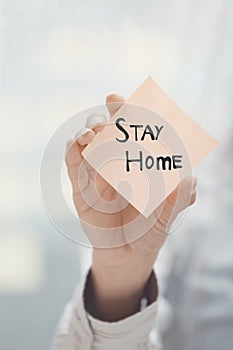 Hand holding sticky note with Stay Home text