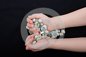 Hand holding stone pebbles gravels in hand on black background