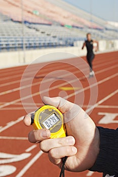 Hand Holding Stopwatch With Runner On Race Track photo