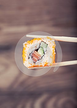 Hand holding sushi roll using chopsticks