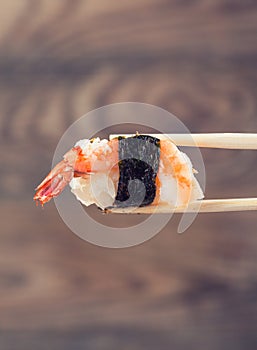 Hand holding sushi roll using chopsticks