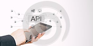 Hand holding tablet with API concept and digital connections in technology background