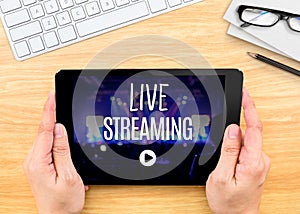 Hand holding tablet with Live Streaming word on wood table ,Internet marketing concept. photo