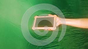 Hand holding tablet, screen, template on a green background. Human hand, modern video background