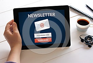 Hand holding tablet with subscribe newsletter concept on screen.