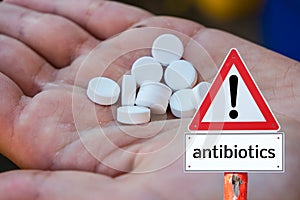 Hand holding tablets and warning sign of antibiotics