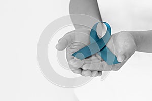 Hand holding teal color ribbon on white background with copy space. Ovarian Cancer Awareness, Gynecological, Uterine Cancer, photo