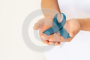 Hand holding teal color ribbon on white background with copy space. Ovarian Cancer Awareness, Gynecological, Uterine Cancer, photo