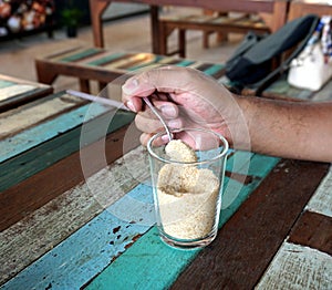 Hand holding teaspoon with sugar