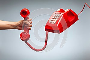 Hand holding telephone, classic red telephone receiver