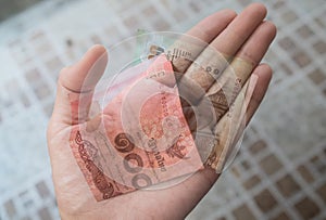 A hand holding Thai Baht bank notes. Added faded effect on the b