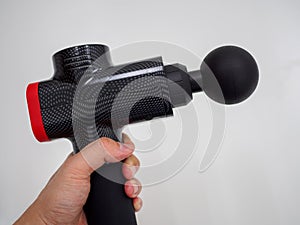 Hand holding a therapeutic massage gun isolated against a white background with copy space