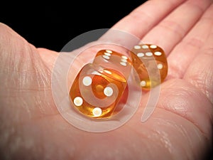 Hand holding three dice on a black background