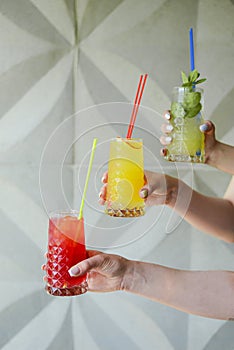 Hand holding three smoothie shake cocktails against a wall. Drinking red healthy smoothie concept. Seasonal cocktail