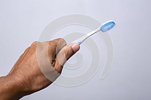 Hand holding toothbrush isolated on gray background