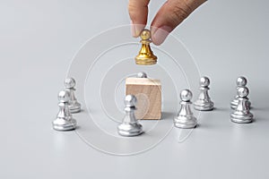 Hand holding top of golden chess pawn pieces or leader businessman. victory, leadership, business success, team, recruiting, and