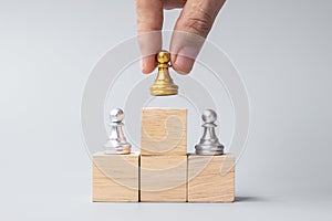 Hand holding top of golden chess pawn pieces or leader businessman. victory, leadership, business success, team, recruiting, and