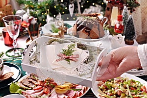 A hand holding a tray with Christmas Eve wafer over the festive table