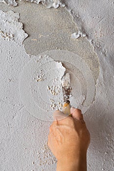 Hand holding trowel and applying skim coat plastering on a wall