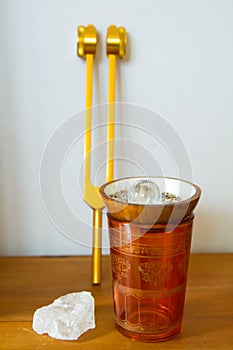 Hand holding a tuning fork and crystal stone  .