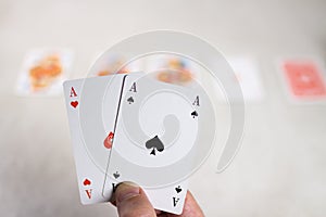 Hand Holding Two Aces in Front of Other Cards