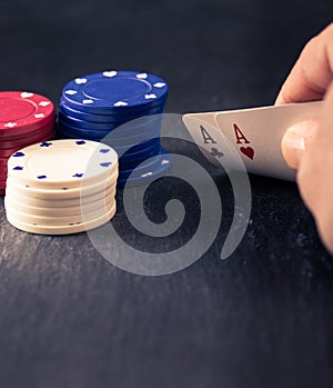 Hand holding two aces, poker chips, retro color look