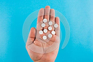 Hand holding two pills over blue background