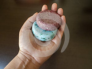 Hand holding two red and blue Shampoo bars before washing their hair in the shower version 2 photo