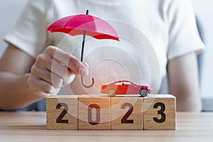 Ruka držanie dáždnik a krytie auto hračka 2023 blokovať na stôl. auto poistenie záruka opraviť finančné bankovníctvo 