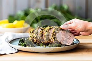 hand holding up a plate with herb crusted pork loin