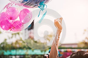 Hand holding up rope of greeting balloon for special event or birthday party. Happiness and celebration party concept. Friendship