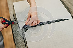 Hand holding up a sheet of baking paper and cut using a pair of scissors