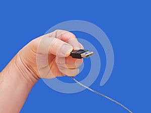 Hand holding USB cable 1-Blue Background