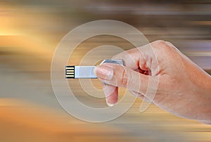 Hand holding USB data storage against bright light and circuit