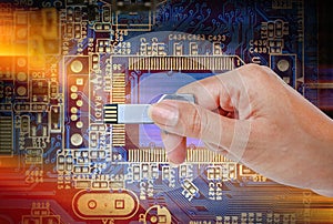 Hand holding USB data storage against bright light and circuit