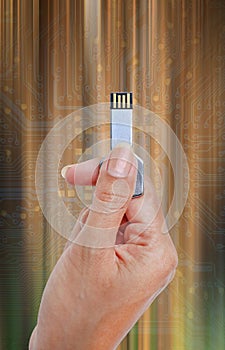 Hand holding USB data storage against light and circuit